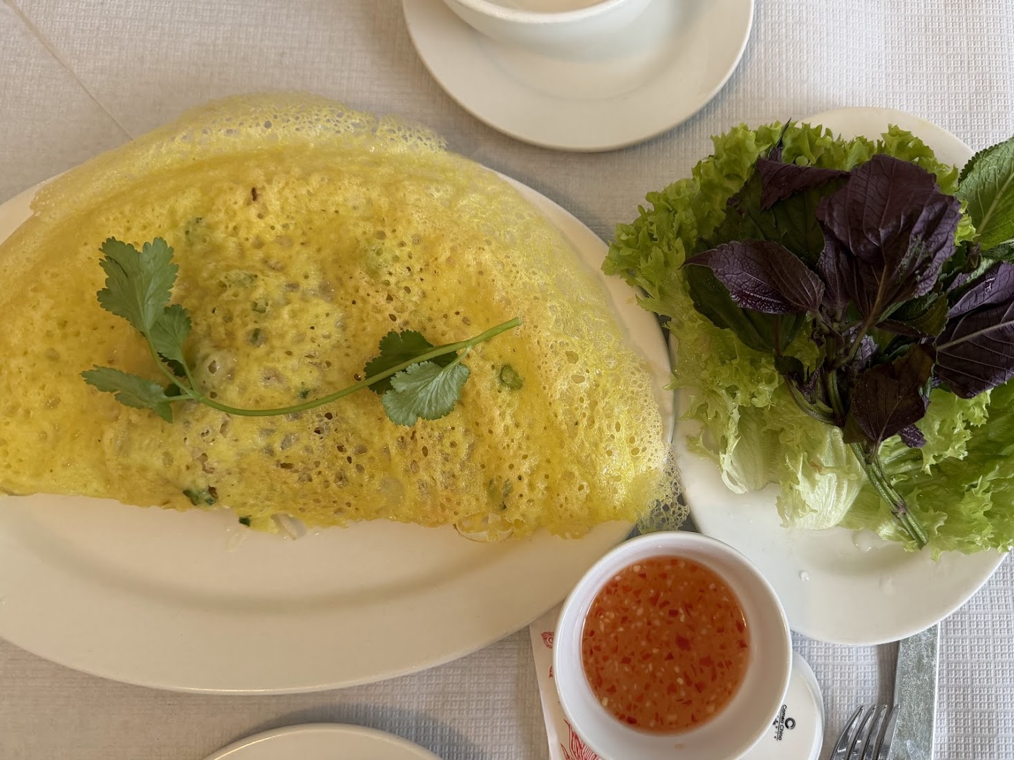 A crispy bánh xèo pancake with herbs